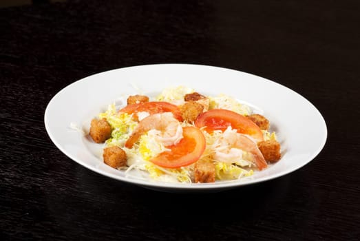 Salad of tiger shrimps, lettuce, chinese cabbage, tomato, garlic rusk, parmesan cheese and sauce