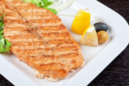 Grilled salmon steak with greens,onion, lemon, lime and olive