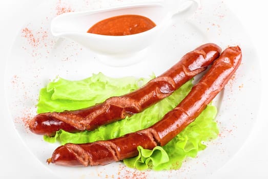 grilled sausages closeup with lettuce and sauce isolated on white