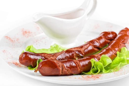 grilled sausage closeup with lettuce and sauce isolated on white