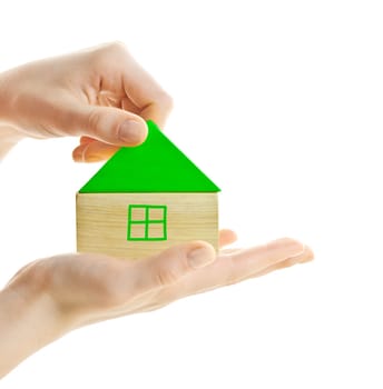 Hand holding green wooden block house isolated on white