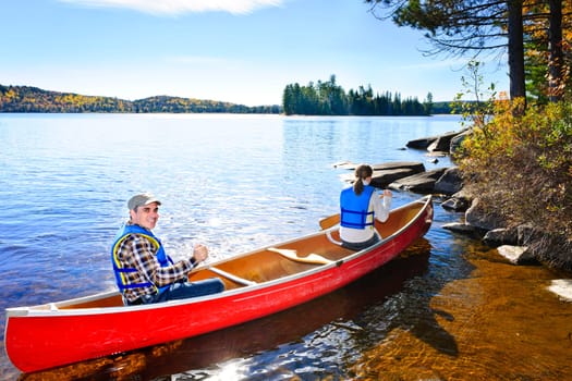 Family in red canoe near rocky shore of Lake of Two Rivers, Ontario, Canada