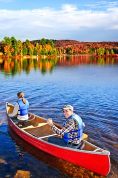 People canoeing on scenic lake in fall, Algonquin park, Canada