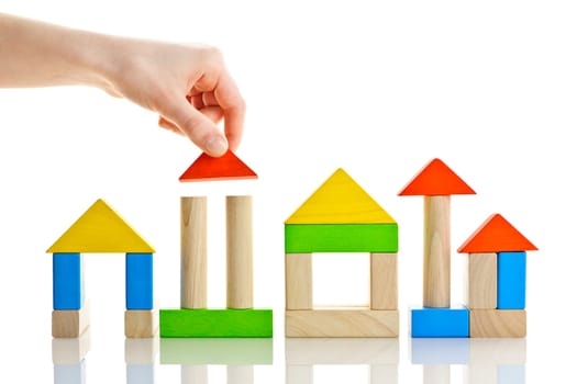 Hand building houses of wooden block toys isolated on white background