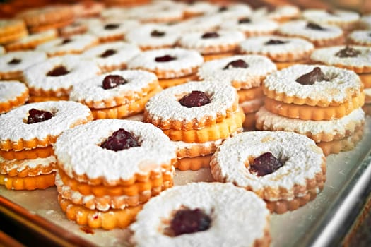 Jam sandwich cookies stacked on a cookie sheet