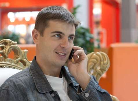 Man smiles with telephone in hand, peers into distance