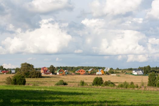 Rural lodges on background of the field with green herb