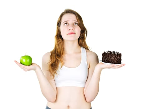 Tempted young woman holding apple and chocolate cake making a choice