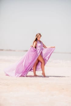 Woman pink salt lake. Against the backdrop of a pink salt lake, a woman in a long pink dress takes a leisurely stroll along the white, salty shore, capturing a wanderlust moment