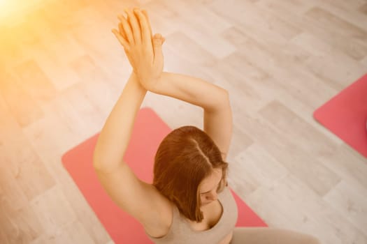 Girl does yoga. Young woman practices asanas on a beige one-ton background