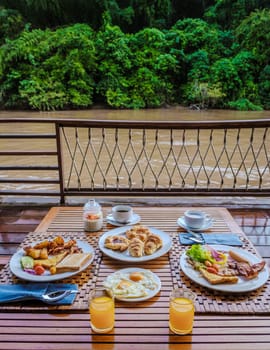 breakfast table at a tropical beach house on the River Kwai in Thailand.Wooden floating raft house in river Kwai Kanchanaburi, Thailand