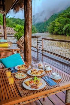 breakfast table at a tropical beach house on the River Kwai in Thailand.Wooden floating raft house in river Kwai Kanchanaburi, Thailand