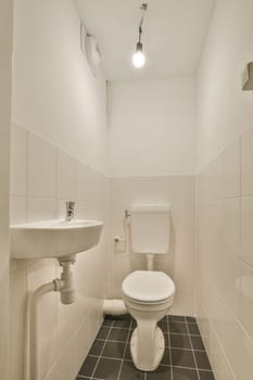 a bathroom with black and white tiles on the floor, sink and toilet in the room is lit by recessed light