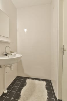 a small bathroom with black and white tiles on the floor next to a sink, mirror and toilet roller