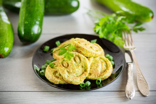 Fried squash green pancakes in a plate, on a wooden table.