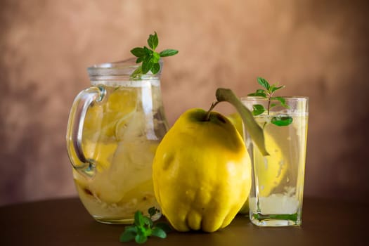 Prepared compote from ripe natural autumn quince, in a glass glass and decanter on a dark wooden table.