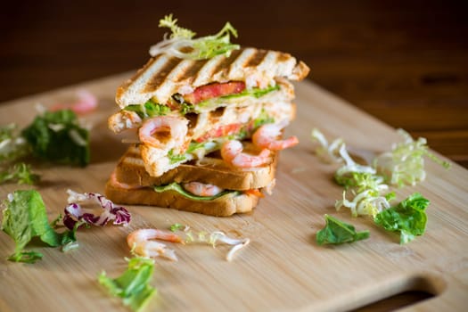 sandwich with lettuce and shrimp on a wooden board