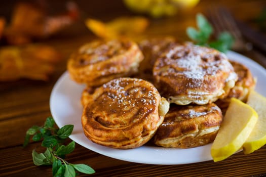 Cooked fried round pancakes with quince filling, cute pancakes with a smile, autumn recipes, on a wooden table