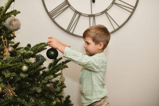 The boy decorates a tree for Christmas