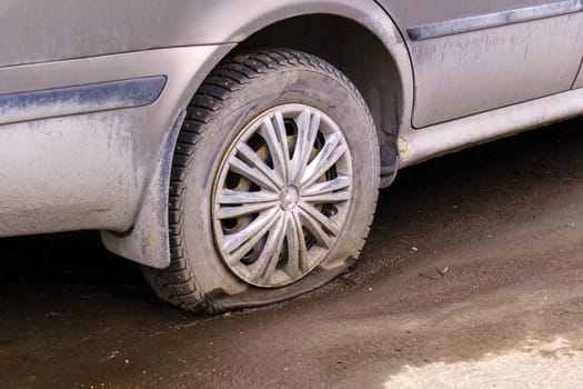 Close up of flat rear tire of car vehicle automobile punctured by nail. Selective focus. Bad luck, accident concept.