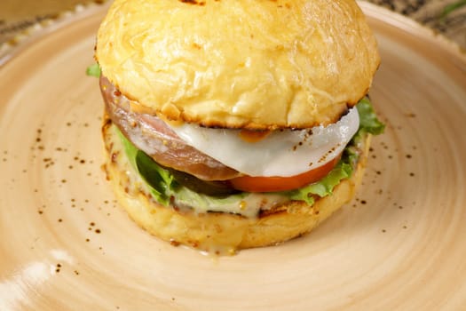 Burger with beef tongue, cheese salad and tomato close-up. Selective focus