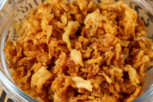 Crispy fried onions in bowl, a pile of freshly chopped onions. Close up