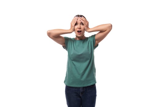 young excited black-haired woman with collected hair is dressed in a basic t-shirt and jeans holding her head.