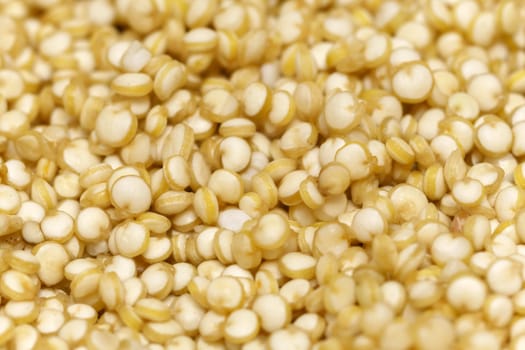 Close-up macro shot of the dry light quinoa grains lying on a flat surface.