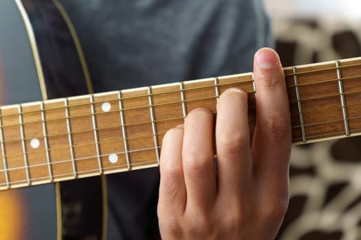 Man plays an acoustic guitar at home, close-up. Selective focus