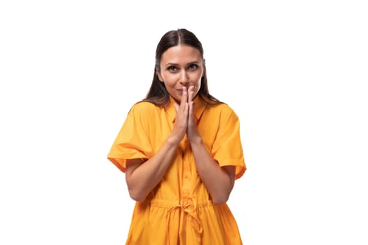 young caucasian brunette woman with long hair is dressed in a yellow summer dress smiling affably.