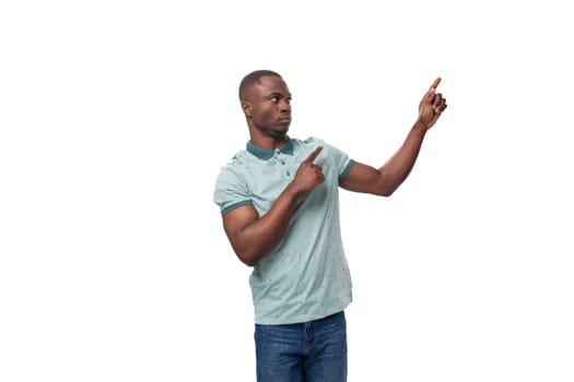 young american man dressed in a t-shirt points his finger at an empty space.