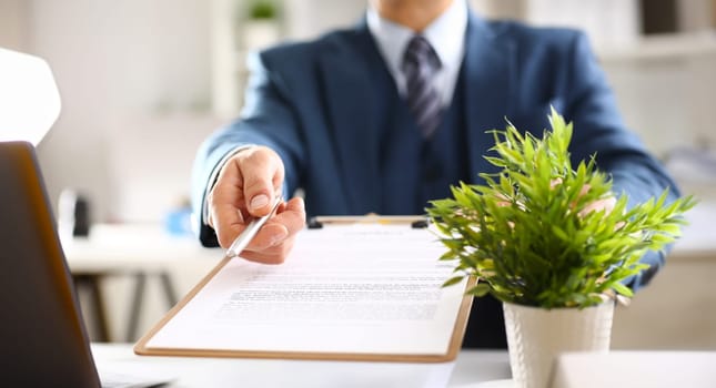 Male arm in suit offer contract form on clipboard pad and silver pen to sign closeup. Strike a bargain for profit white collar motivation union decision corporate sale insurance agent concept