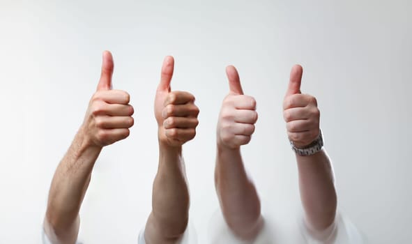 A group of people male hands on a gray background holds a thumb up expressing agreement finger OK concept is large closeup concept