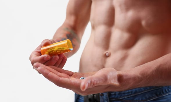 Fitness man pours pills from the jar into hand intake of hormonal preparations for rapid growth. Of doping muscles to achieve high results is experiencing problems with potency after closeup concept.