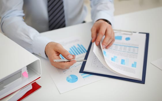 Male hands hold documents with financial statistics at office workspace closeup. White collar check money papers stock exchange market internal Revenue Service inspector earning list concept