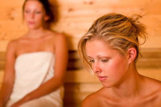 Sauna two healthy beautiful women relaxing sweating covered towels
