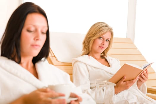 Beauty health spa treatment two women relax sun-beds coffee book