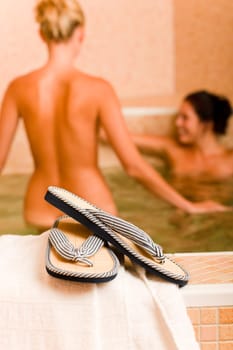 Flip-flops close-up relax spa pool two naked women inside water