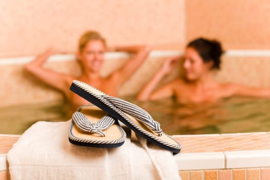 Flip-flops close-up relax spa pool two naked women inside water
