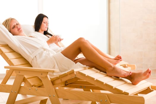 Two beautiful women relax sitting on sun-beds healthy luxury spa