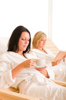 Beauty health spa treatment two women relax sun-beds coffee book