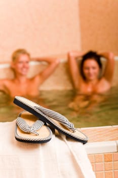 Flip-flops close-up relax spa pool two naked women inside water