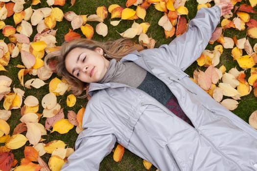 Beautiful girl rests upon autumn sheet and green herb