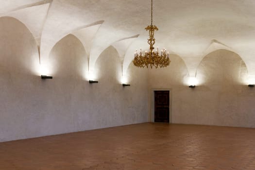 Room in the castle with a gold chandelier and candlesticks on the walls