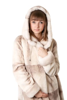 A beautiful young girl in a fur coat on a white background