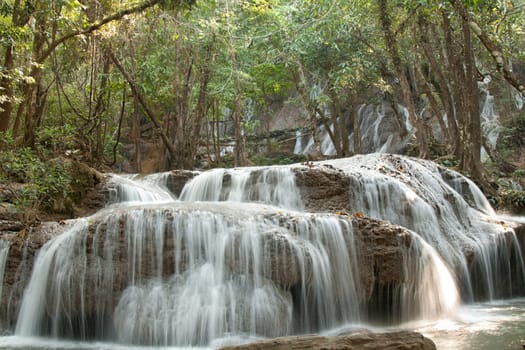 Waterfall in jungle in Thailand, sunshine entrenches through foliage