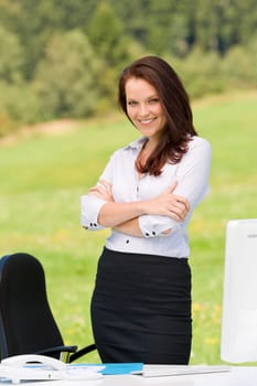 Young businesswoman in sunny nature behind table smiling crossed arms