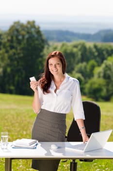 Young businesswoman in sunny nature office calling standing behind table