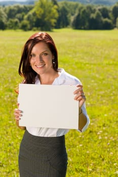 Young businesswoman sunny meadow holding aside blank advertising banner