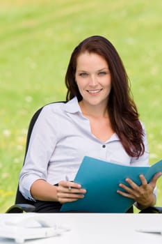 Young businesswoman in nature attractive smiling holding folder behind table
